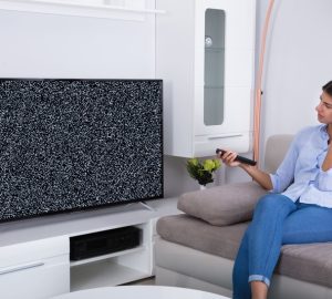 La TV si sente ma non si vede, donna sul divano guarda triste la tv che non si vede