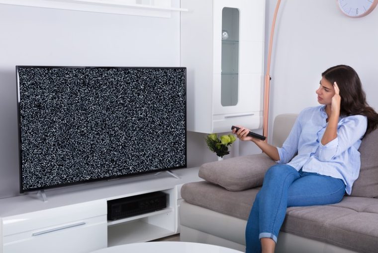 La TV si sente ma non si vede, donna sul divano guarda triste la tv che non si vede