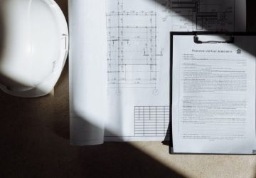 Aggiornamento catastale con DOCFA: i casi in cui serve davvero: Vista dall'alto di documenti di costruzione e casco alla…