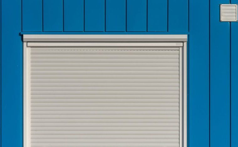 Tapparelle pulite senza smontarle con un lavaggio semplice: Un muro blu moderno con un saracinesca bianca chiusa, perfetto…